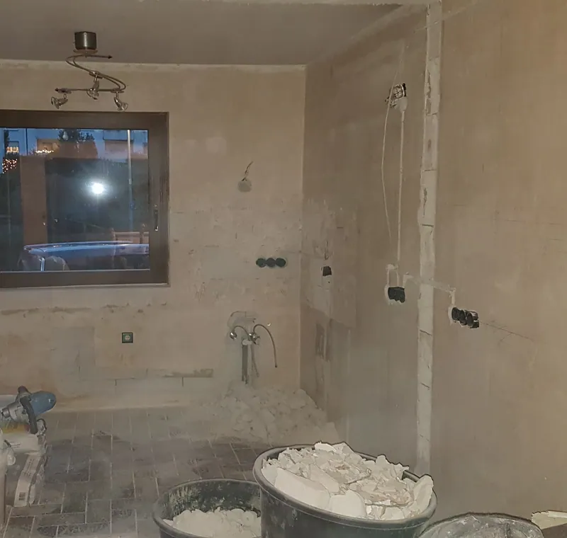Entkerntes Bad mit abgeschlagenen Wänden, Fenster und Eimern mit Bauschutt