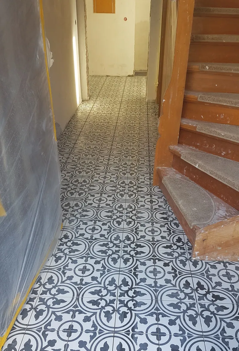 Flur im Altbau mit schwarz-weiß gemusterten Zementfliesen neben einer Holztreppe