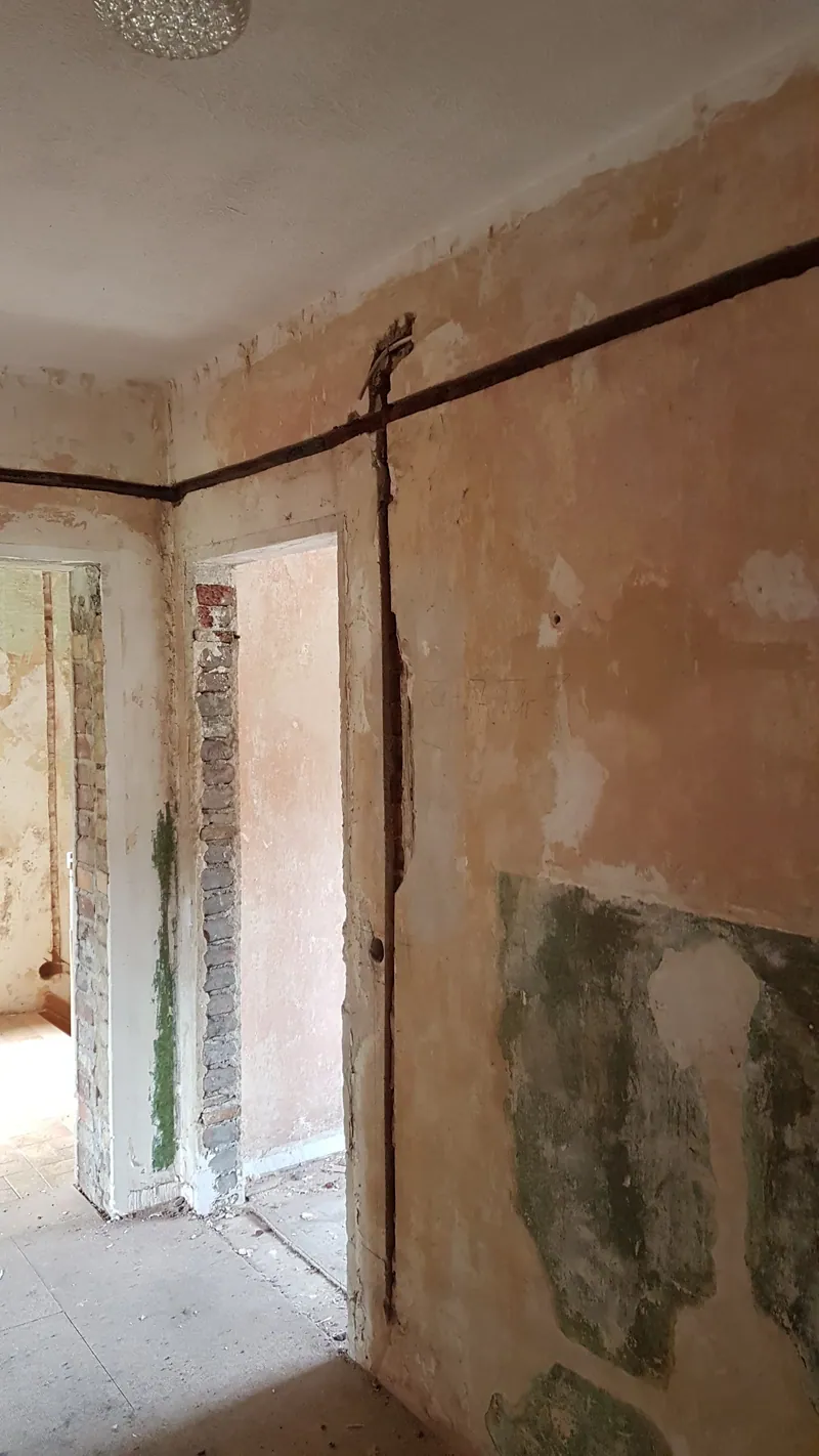Rohbauwand mit geschlitzten Kabelkanälen und freigelegtem Putz in einem Altbau
