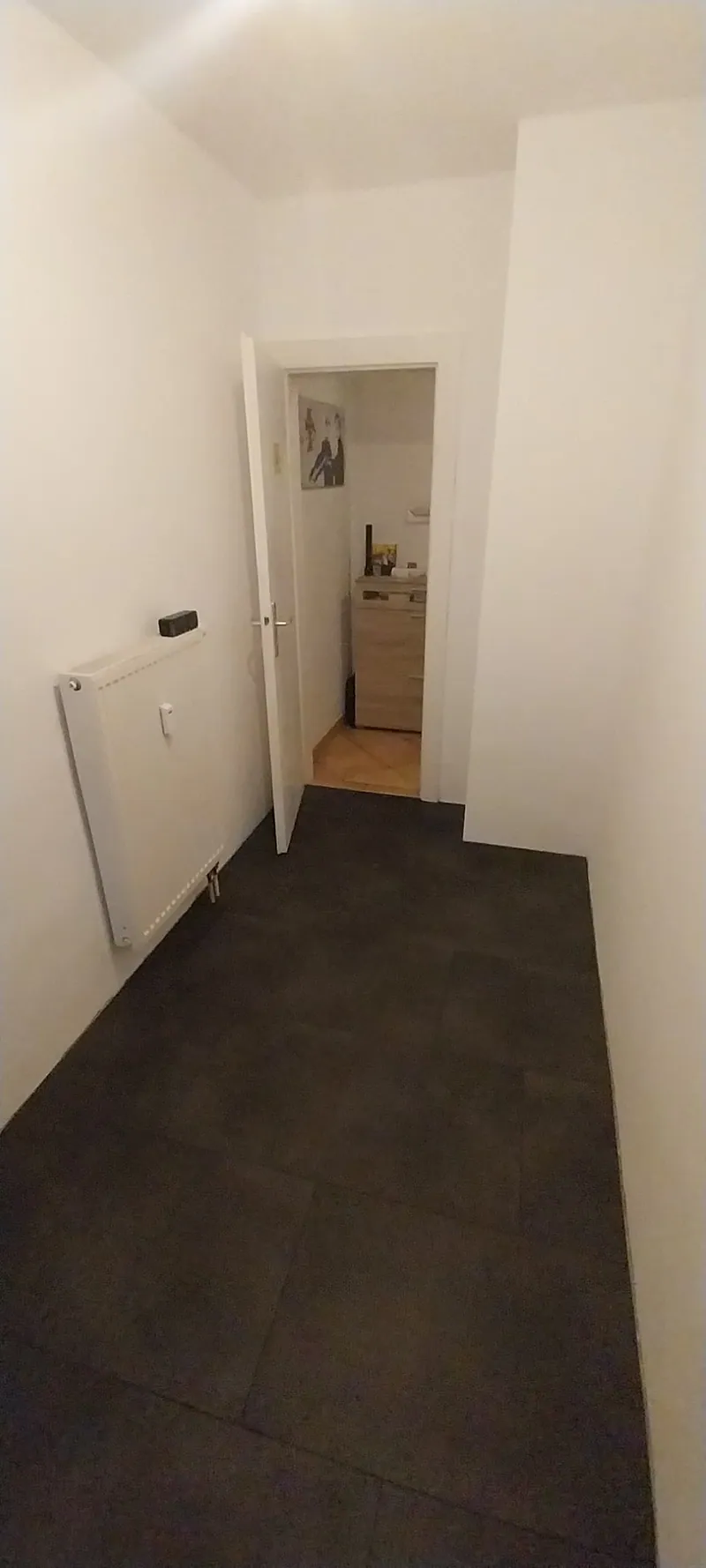 Schmaler Raum mit dunklen großformatigen Bodenfliesen