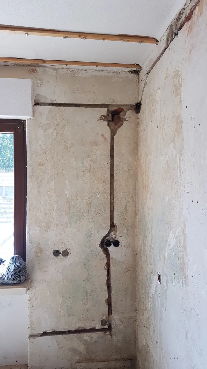 Wand mit senkrechten Leitungsschlitzen und Unterputzdosen neben einem Fenster