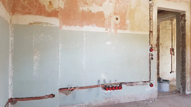 Wand mit Leitungsschlitzen, rot markierten Steckdosendosen und Durchgang