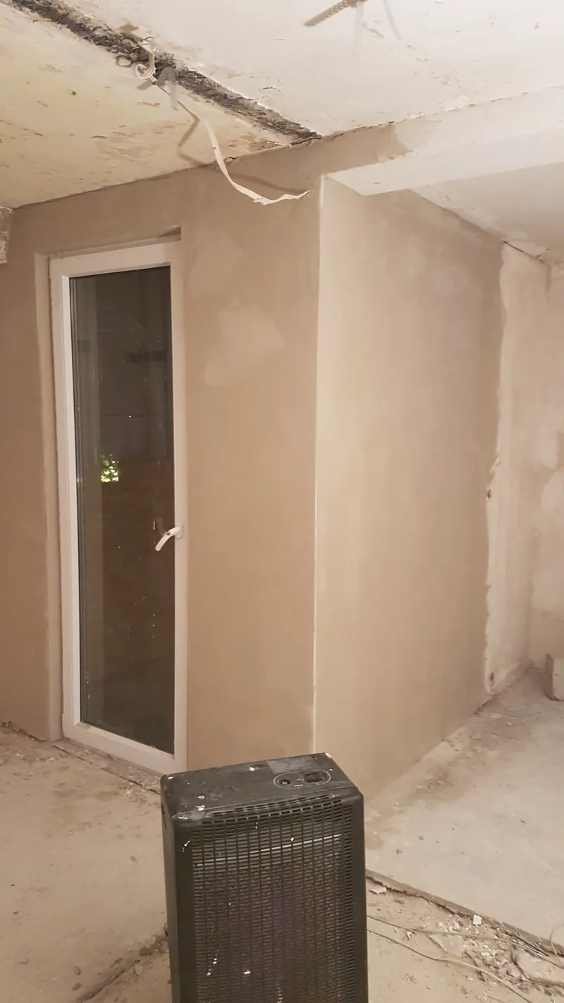 Verputzter Rohbauraum mit Fenstertür und Bauheizgerät