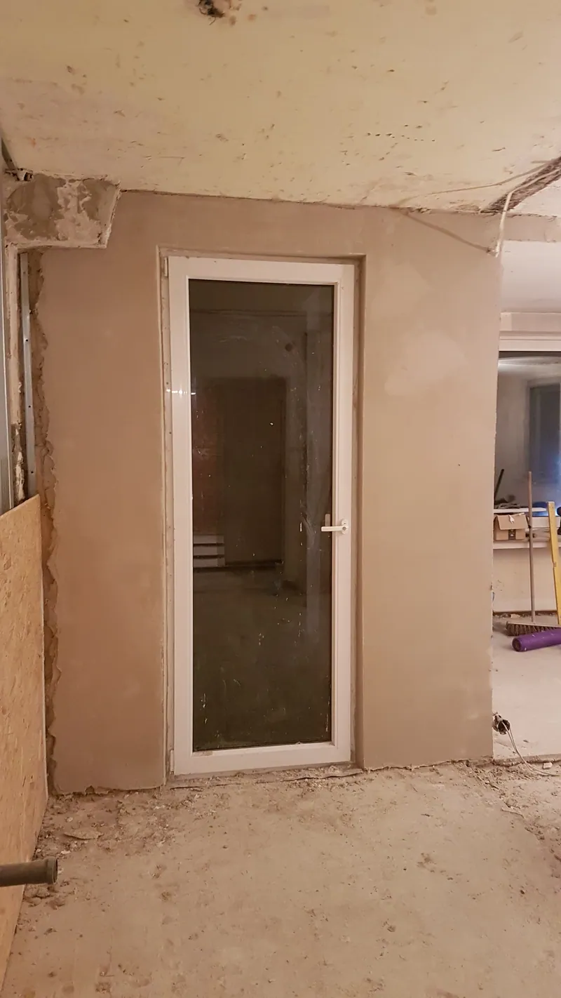 Verputzte Trennwand mit Glastür in einem Rohbau