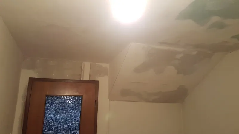 Spachtelarbeiten an einer Dachschräge, daneben eine Holztür mit Ornamentglas