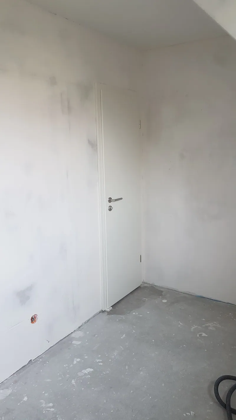 Gespachtelte Trockenbauwand mit weißer Tür in einem leeren Raum