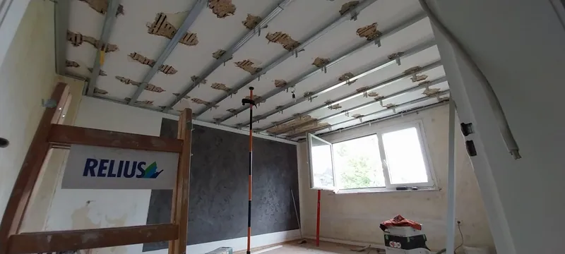 Raum mit Unterkonstruktion für eine abgehängte Decke aus Metallprofilen und dunkler Wand