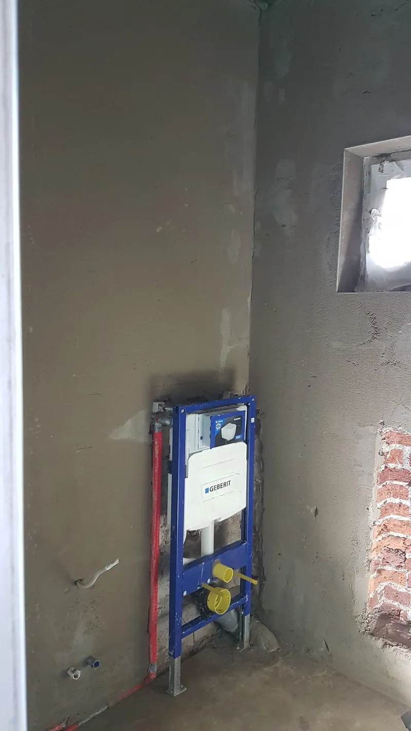 Bad im Rohbau mit WC-Vorwandinstallation und grauer Plattenwand