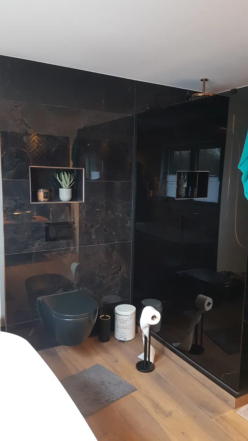 Bad mit dunklen großformatigen Fliesen in der Dusche und Holzoptik-Boden